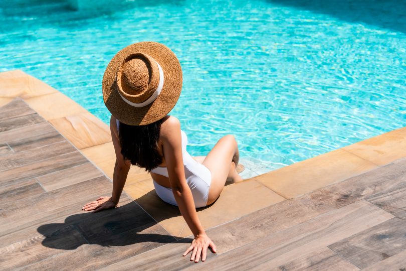 Frau mit Hut am Pool